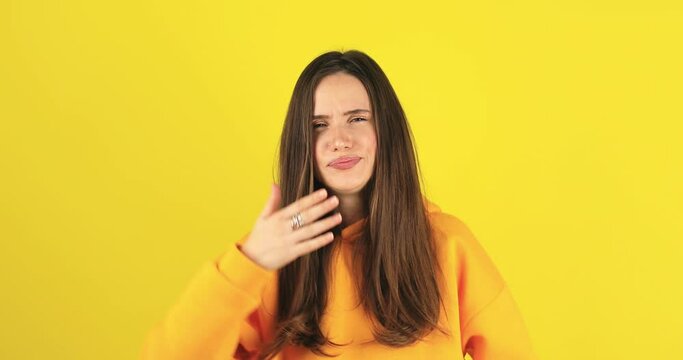 Tired exhausted young caucasian woman yawning, sleepy inattentive feeling somnolent lazy bored gaping suffering from lack of sleep, insomnia. Brunette girl isolated on yellow studio background indoors