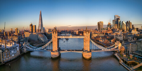 Aerial front view of the Tower Bridge of London with the skyline behind reflecting the golden...