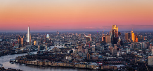 Wide panoramic view of the London skyline during dawn with pink colors and soft sunlight reflecting from the City skyscrapers, England