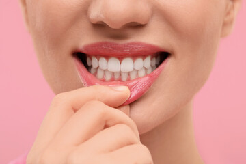 Obraz premium Beautiful woman showing her clean teeth on pink background, closeup