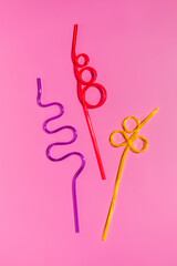 Colorful plastic cocktail straws on a pink background. Flat lay