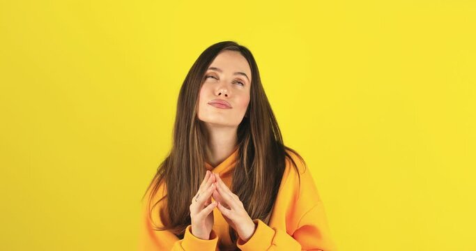 Mysterious sly woman steeple fingers and schemes something tries to made up mind makes devious tricky plan isolated over yellow background. Evil genius action. Girl in yellow hoody have idea.