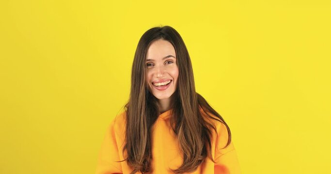Smiling happy young brunette girl wears yellow hoody scream hot news about sales discount with hand near mouth isolated on yellow background. Lifestyle emotions, announce. Attention! Sale!