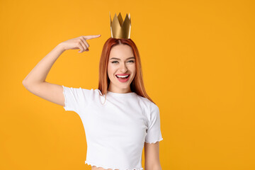 Beautiful young woman with princess crown on orange background