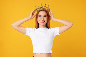 Beautiful young woman with golden crown on orange background