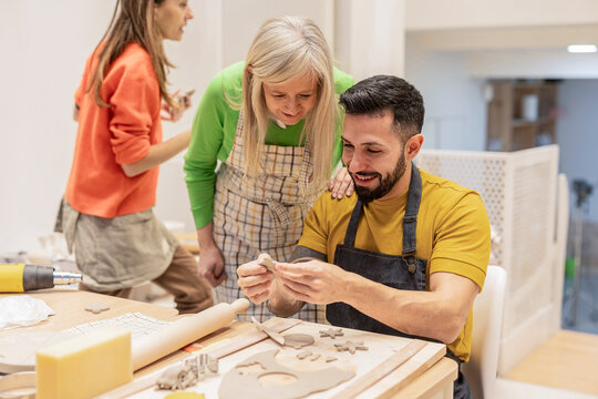 group of adults working in ceramic workshop, multigenerational group of people enjoying their hobby with clay learning in class - Powered by Adobe
