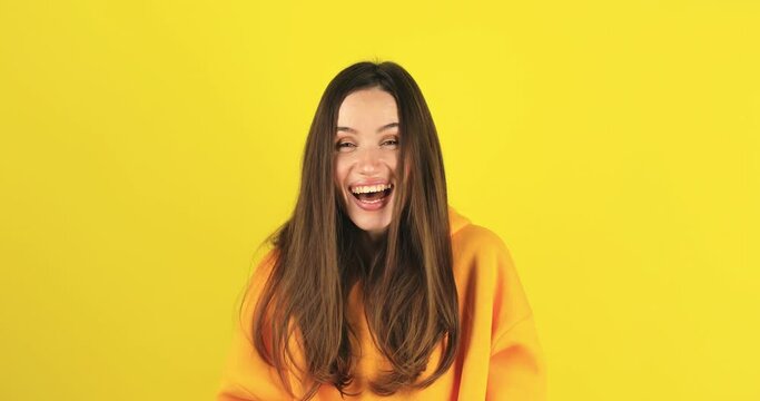Amazed excited woman hairstyle in yellow hoody open mouth in surprise looking at camera with big eyes, shocked isolated on yellow background. Oh my god wow, yes gesture, win symbol.