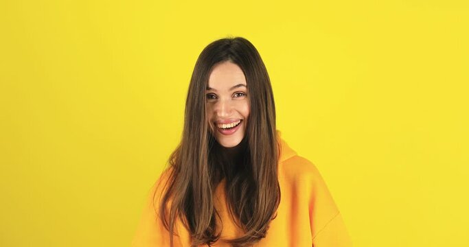 Amazed excited woman hairstyle in yellow hoody open mouth in surprise looking at camera with big eyes, shocked isolated on yellow background. Oh my god wow, yes gesture, win symbol.