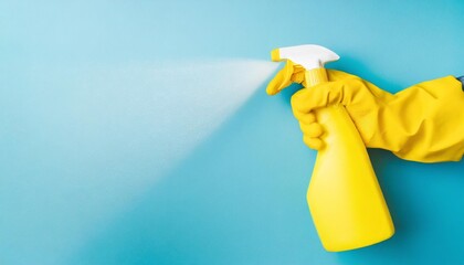 hand in yellow glove with spray on blue background with copy space cleaning concept - obrazy, fototapety, plakaty