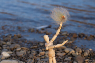 Mannequin lifting dandelion to the top on the background of the river, concept of joy, hope.