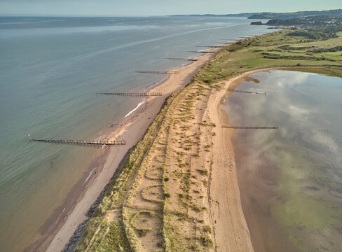 Aerial view of beach and dunes at Dawlish Warren, guarding the mouth of the River Exe, looking south along the coast towards the town of Dawlish, Devon, England