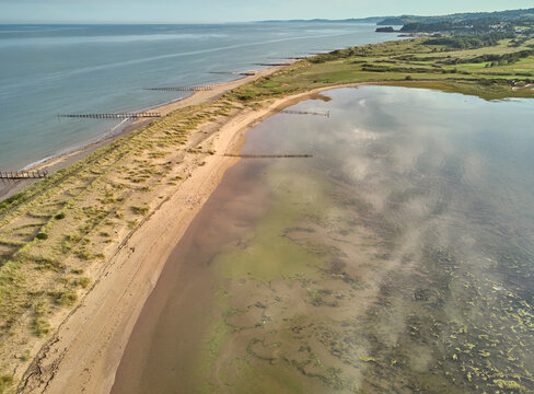 Aerial view of beach and dunes at Dawlish Warren, guarding the mouth of the River Exe, looking south along the coast towards the town of Dawlish, Devon, England