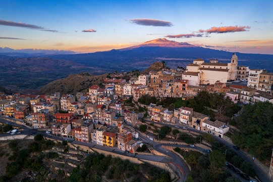 Aerial view of the old village of Centuripe with Mount Etna volcano Etna covered with snow and lit from the sunset, Centuripe, Enna province, Sicily, Mediterranean