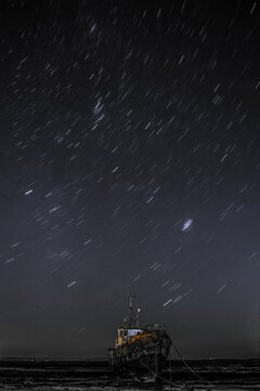 Star trails above the derelict trawler Vita Nova, from the Cumbrian Coast, Furness Peninsula, Cumbria, England