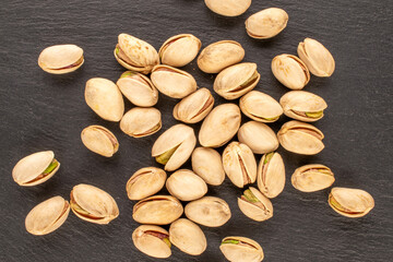 A few tasty pistachios on a slate stone, macro, top view.