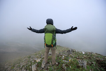 Woman hiker enjoy the view on mountain top cliff edge face the snow capped mountains in tibet