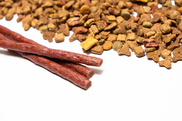 Treats for cats meat sticks sausages against the background of dry food. Complete diet for adult cats