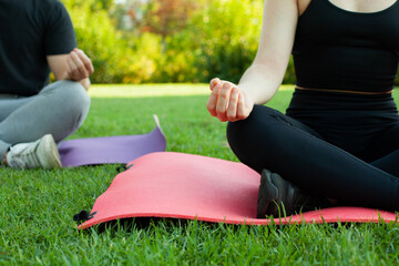 Pareja de chico y chica haciendo yoga en el parque al aire libre. Deporte con esterillas. Descanso en esterilla. Estilo de vida saludable.