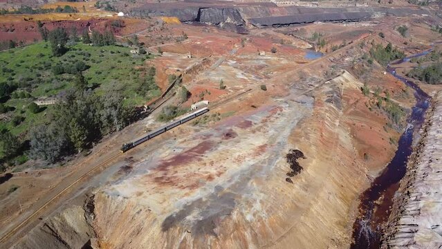 Aerial drone view of the old tourist train on a tour of the remains of the copper mine exploitation named Corta Atalaya, in the town of Minas de Riotinto in the province of Huelva
