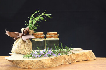 Rosemary essential oil in glass bottle on dark background