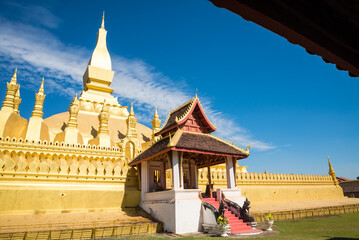 Naklejka premium Beautiful large golden pagoda Pha That Luang temple famous landmark in Vientiane, Laos PDR sunny day blue sky background. Travel destination and religion in Asia concept.