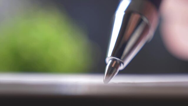 Ballpoint pen. Person signs a document on paper, shallow depth of field