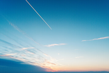 Clear view of the Sky during a beautiful sunset with a plane flying through the sky to the horizon