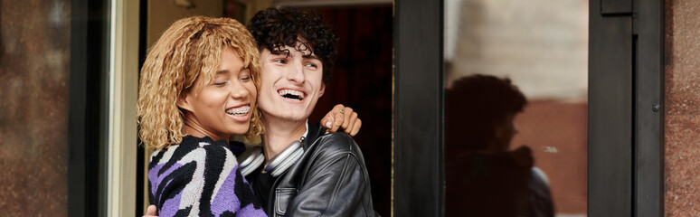 happy diverse couple in casual wear hugging by the entrance of vegan cafe, coffee date banner