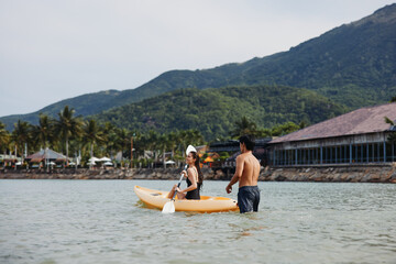 Kayaking Harmony: A Joyful Asian Couple Paddling in the Serene Tropical Waters