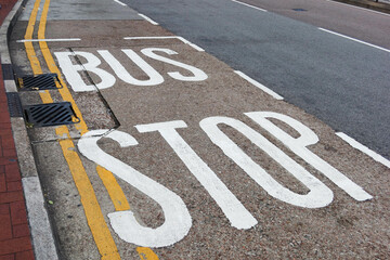 Fototapeta premium white bus stop words sign painted on the road with two yellow lines along the pavement 