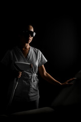 Woman master of laser hair removal in protective glasses holds a photo epilator