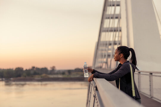 Woman drinking water and enjoying sunrise while going for morning workout session