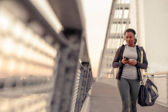 Woman listening to the music and using smart phone while going for morning workout