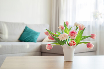 pink spring flowers in white ceramic vase in modern home interior