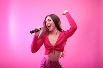 Emotional woman with microphone singing on pink background - Powered by Adobe