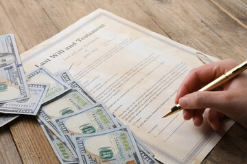 Obraz premium Woman signing Last Will and Testament at wooden table, closeup