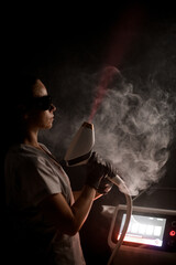 Cosmetologist directs the laser beam of the photoepilator at the ceiling close-up