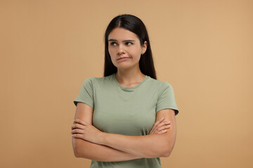 Obraz premium Portrait of resentful woman with crossed arms on beige background