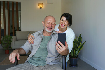 Portrait of joyful mid adult couple on the video call at home. Happy husband and wife smiling at...