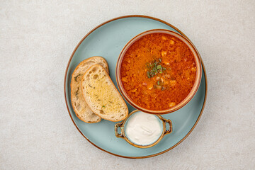 Portion of slavic traditional red sour soup borscht with toast and cream