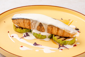 Portion of gourmet salmon steak on zucchini with creamy sauce