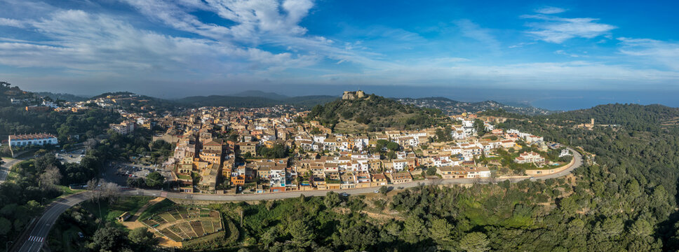 Aerial view of 16th-century Begur castle fort atop a forested hill, with panoramic views of the Mediterranean Sea. Watch towers built against the pirates