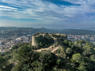 Aerial view of 16th-century Begur castle fort atop a forested hill, with panoramic views of the Mediterranean Sea. Watch towers built against the pirates