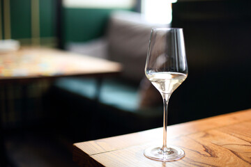 Transparent drink in glass goblet on wood background