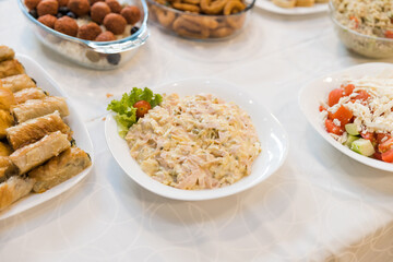 Variety of delicious dishes displayed on a buffet table, including a creamy pasta salad, crispy appetizers, and fresh salads.