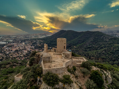 Aerial sunset view of the remains of a small, 11th-century Burriac castle, chapel on a hill, with a modest hike and dramatic views