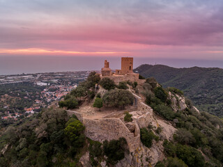 Obraz premium Aerial sunset view of the remains of a small, 11th-century Burriac castle, chapel on a hill, with a modest hike and dramatic views