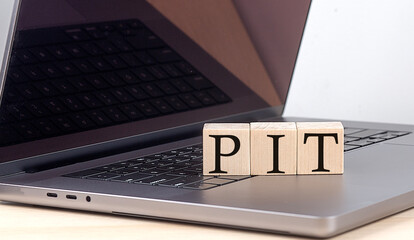 PIT word on wooden block on laptop, business concept - obrazy, fototapety, plakaty