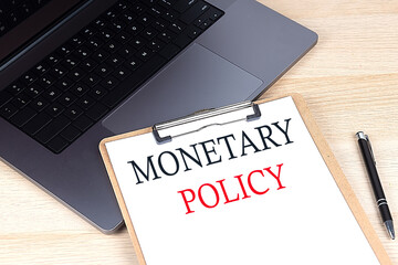 MONETARY POLICY text written on a paper clipboard on laptop