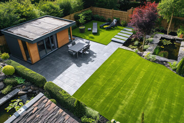 high view of a back garden with artificial grass, grey paving slab patio, summer house garden timber outbuilding, fish pond - obrazy, fototapety, plakaty